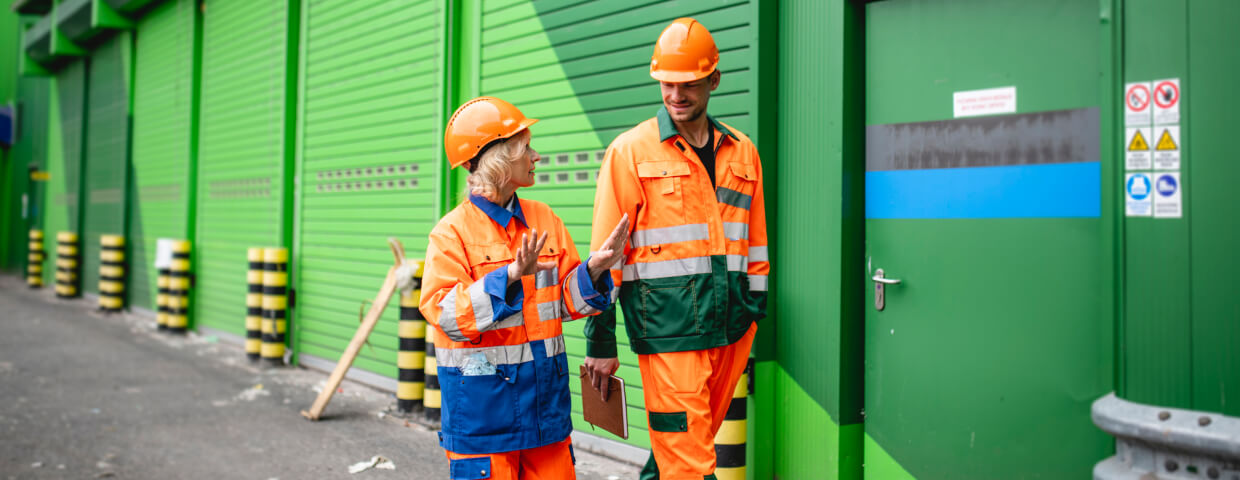 Two workers walking next to green building