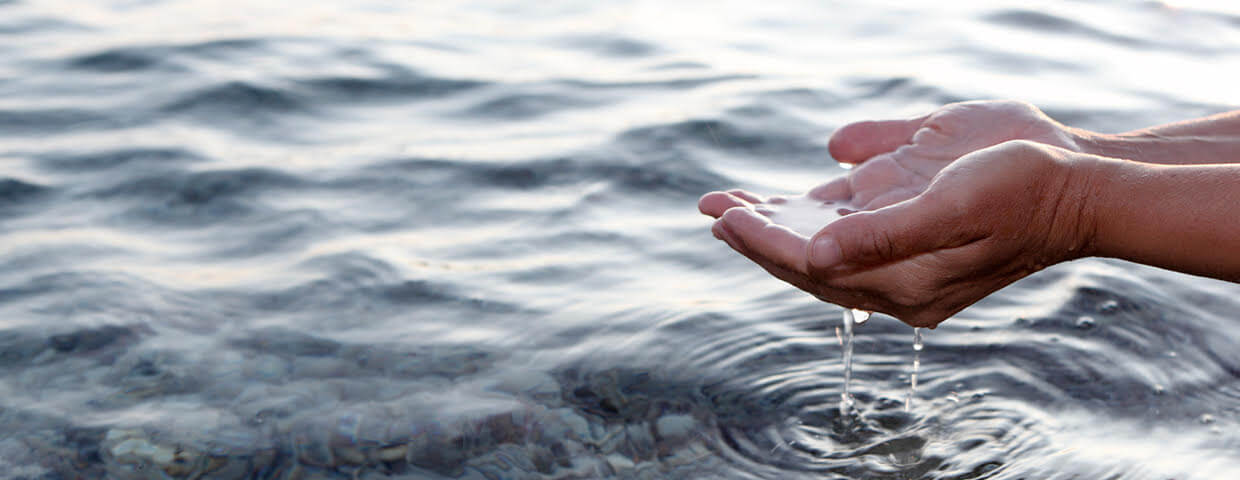 Hands cupping water over source